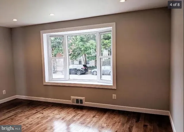 an empty room with wooden floor and a window