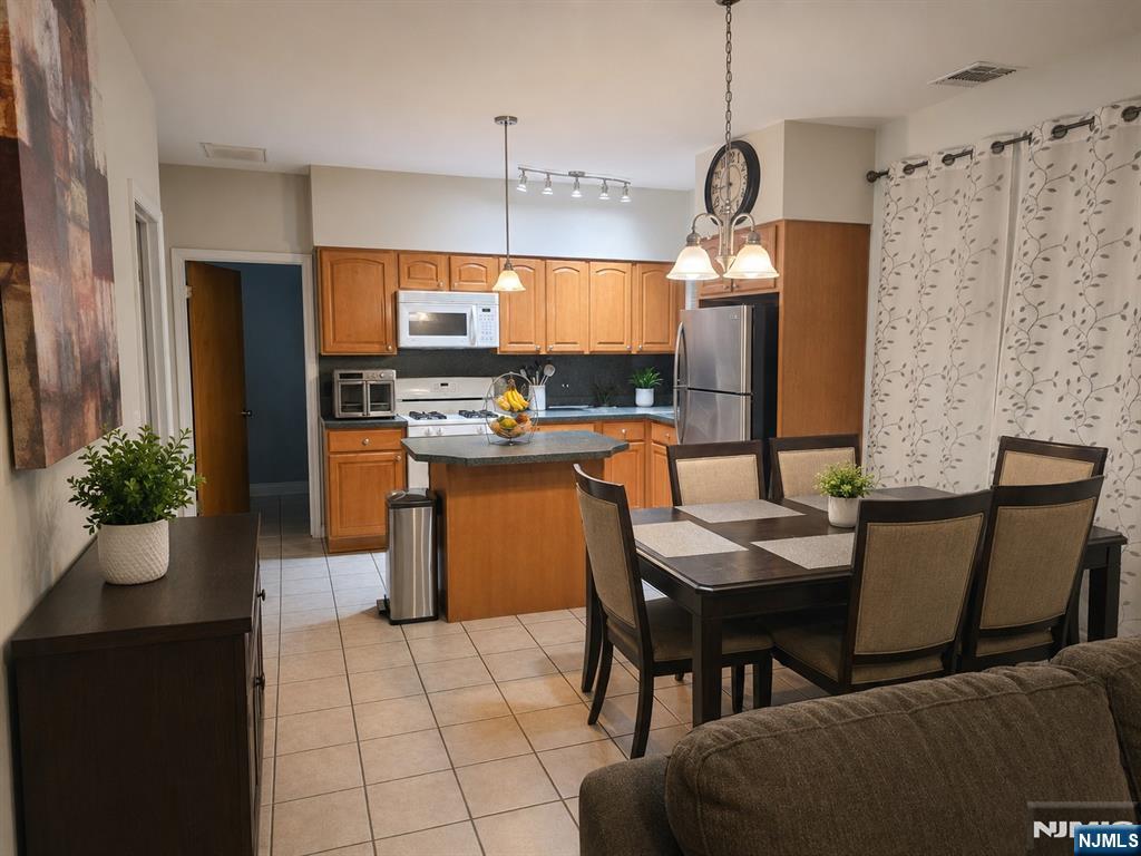 9 Schuyler Court, Unit R2 Kearny, NJ 07032 - Photo 2 of 6 a dining room with granite countertop kitchen island stainless steel appliances a table chairs and a refrigerator