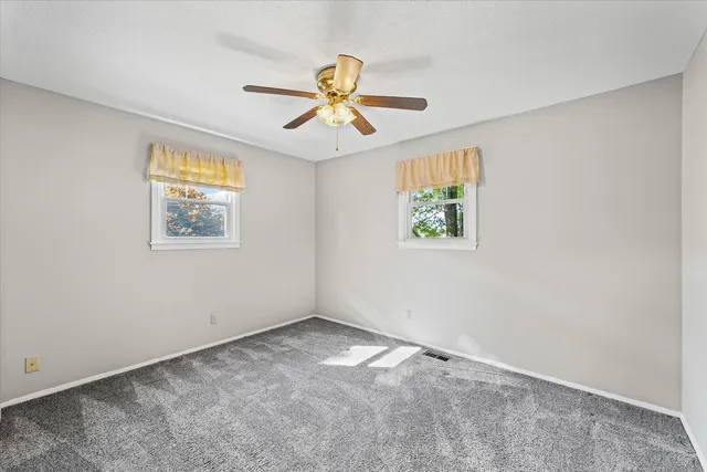 an empty room with windows and a ceiling fan
