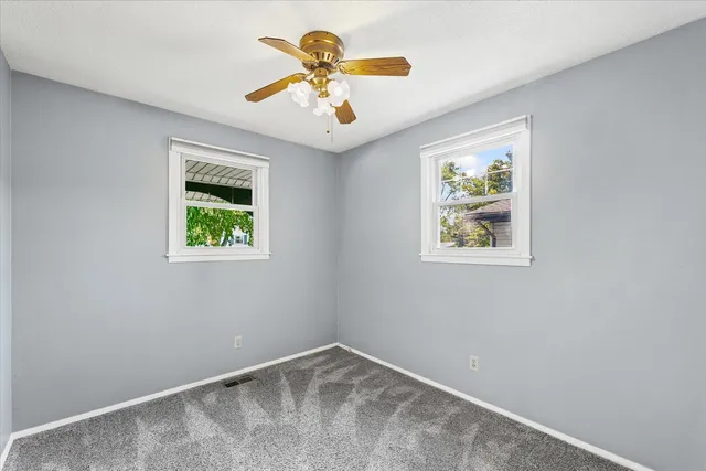an empty room with a window and a ceiling fan