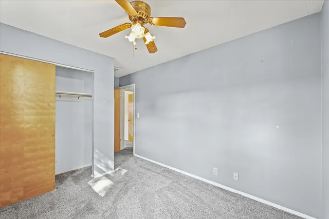 an empty room with a chandelier fan and closet