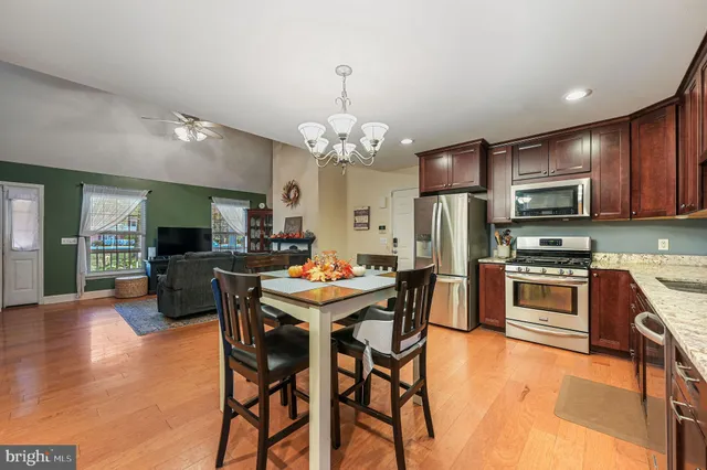 a kitchen with stainless steel appliances kitchen island granite countertop a table chairs and a refrigerator