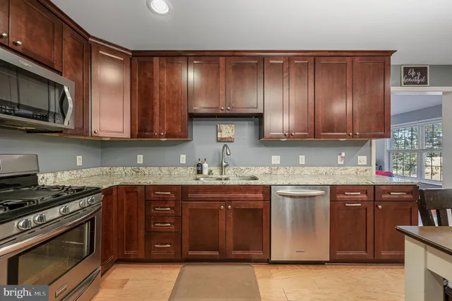 a kitchen with stainless steel appliances granite countertop wooden cabinets a stove top oven a sink and dishwasher