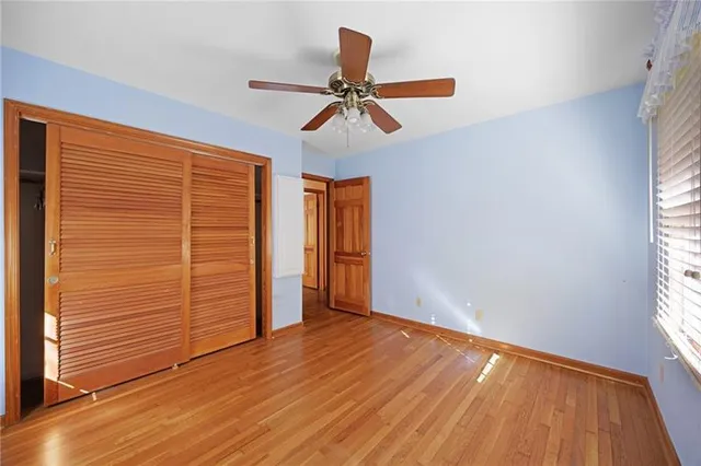 an empty room with wooden floor closet and windows