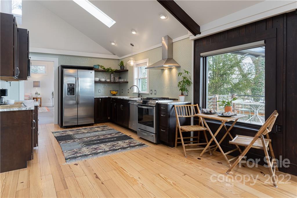 170 South Delano Road Asheville, NC 28805 - Photo 14 of 48 a kitchen with stainless steel appliances granite countertop a stove top oven a sink dishwasher a dining table and chairs with wooden floor