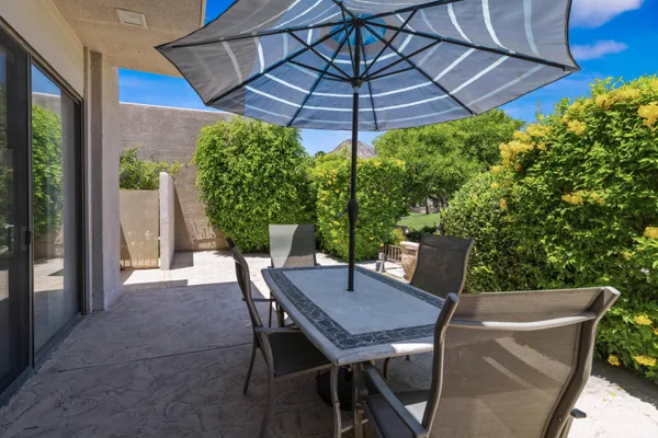 a view of a patio with table and chairs under an umbrella
