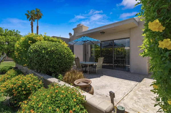 a patio with table and chairs and potted plants