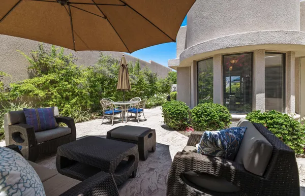 a view of a patio with couches table and chairs under an umbrella