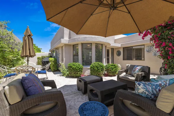 a view of a patio with couches table and chairs under an umbrella