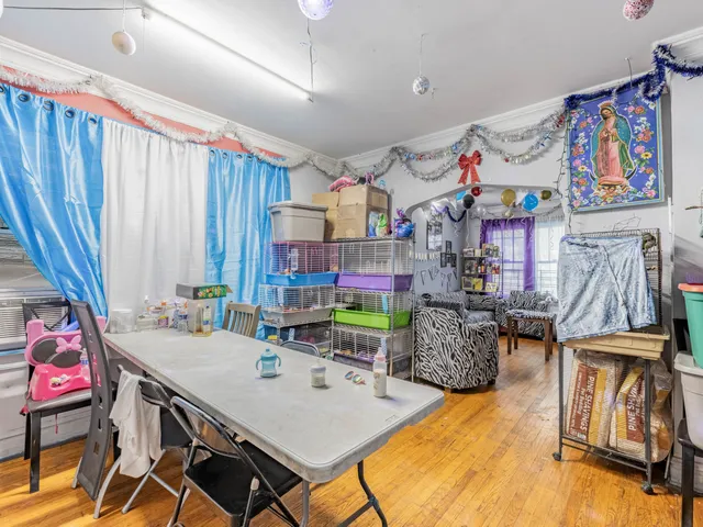 a view of a dining room with furniture one side kitchen view and wooden floor