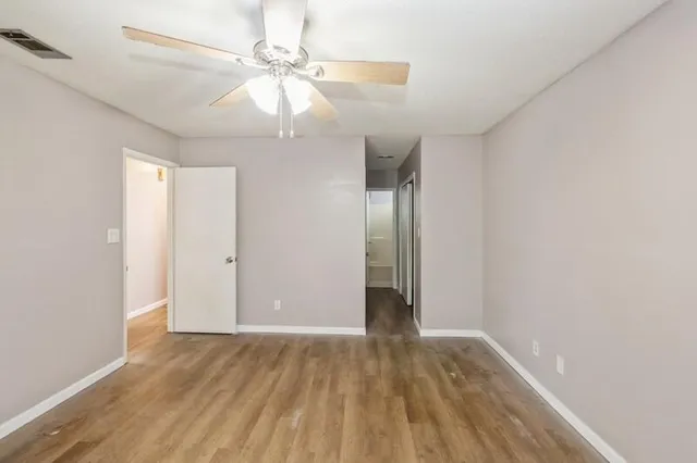 an empty room with wooden floor fan and window