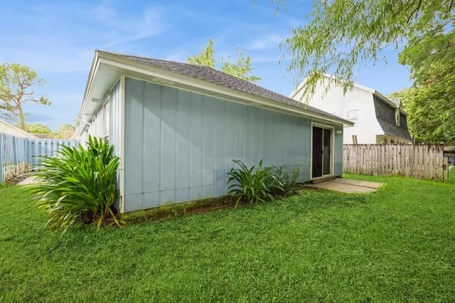 a backyard of a house with plants and palm tree