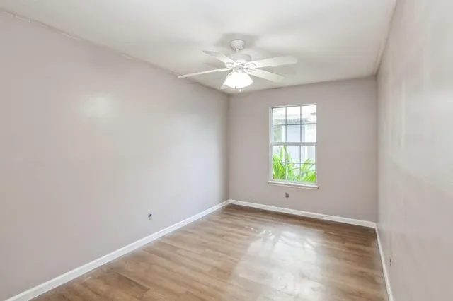 an empty room with windows and fan