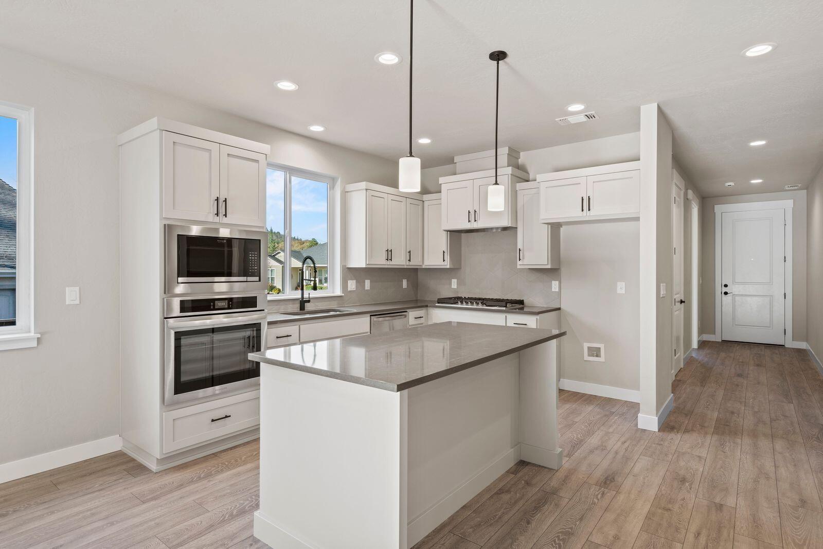 1135 Pumpkin Ridge, Unit 319 Eagle Point, OR 97524 - Photo 8 of 34 a kitchen with stainless steel appliances granite countertop a refrigerator a stove a sink and white cabinets with wooden floor