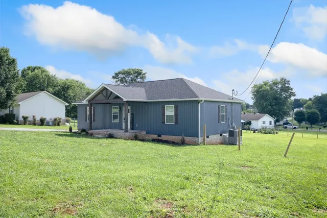 a view of house with a big yard and potted plants