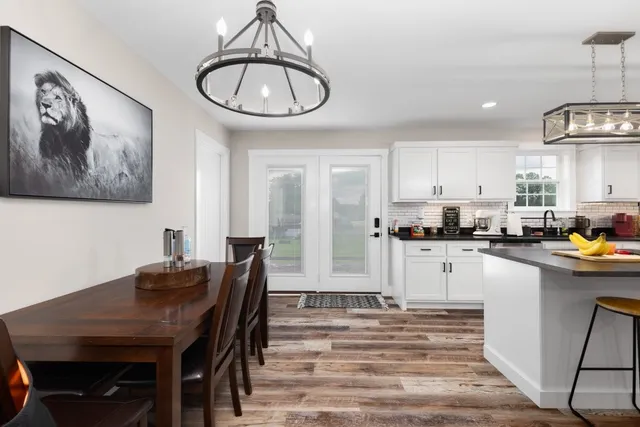 a kitchen with stainless steel appliances granite countertop a dining table chairs and a refrigerator