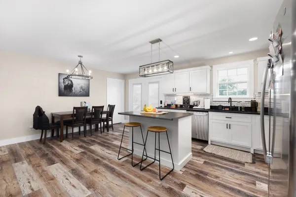 a kitchen with cabinets a sink dishwasher a dining table and chairs with wooden floor