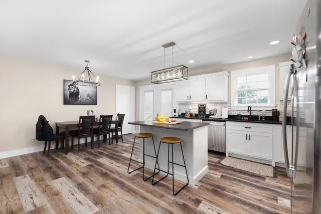 a kitchen with cabinets a sink dishwasher a dining table and chairs with wooden floor