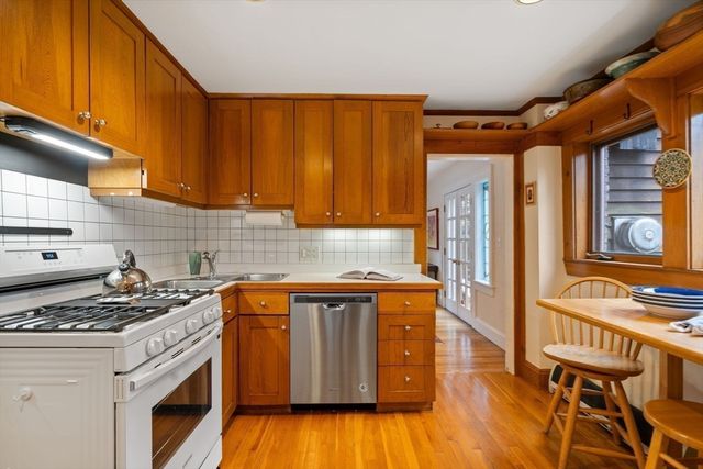 a kitchen with a stove a sink and wooden floor