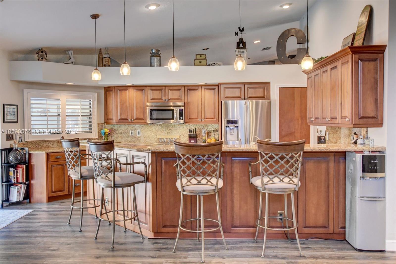 22324 Boyaca Avenue Boca Raton, FL 33433 - Photo 2 of 51 a kitchen with stainless steel appliances kitchen island granite countertop a refrigerator a stove a oven with white cabinets and wooden floor
