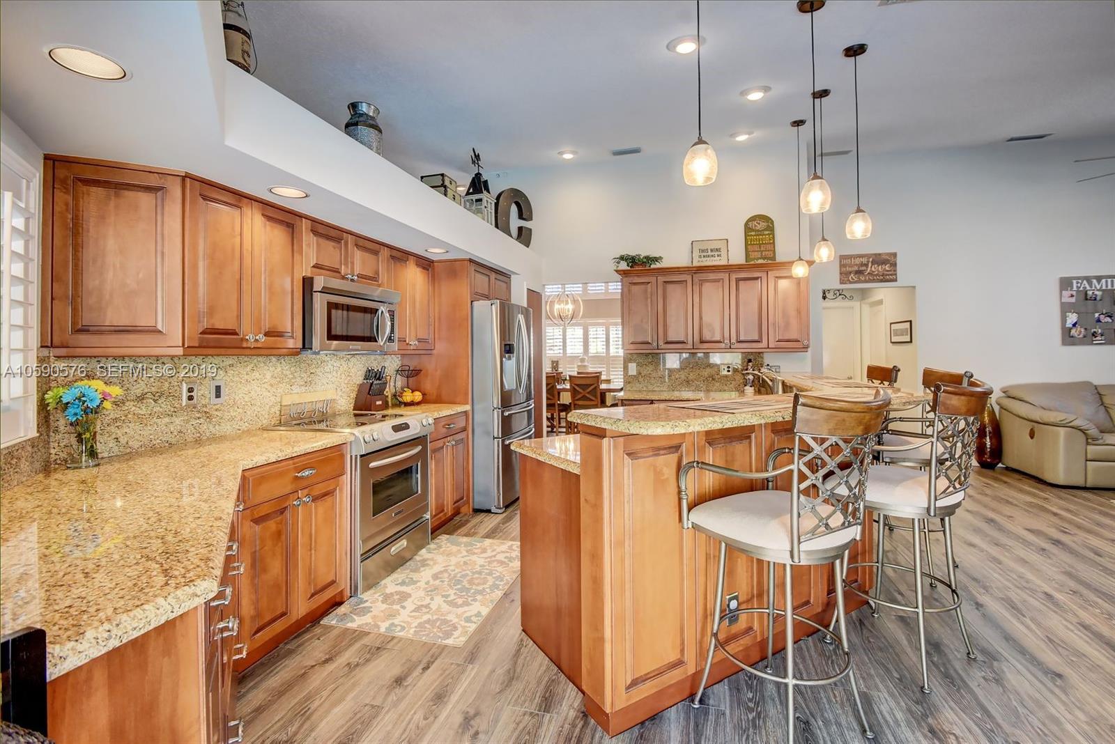 22324 Boyaca Avenue Boca Raton, FL 33433 - Photo 3 of 51 a kitchen with stainless steel appliances granite countertop a stove top oven a sink dishwasher and white cabinets with wooden floor