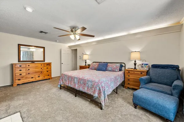 a spacious bedroom with a bed a couch and a chandelier