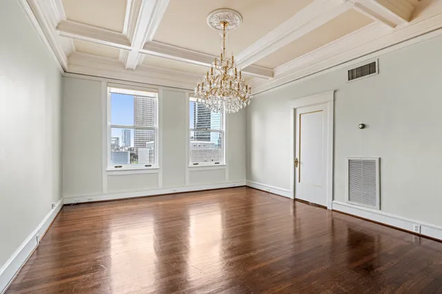 a view of a room with wooden floor chandelier and windows