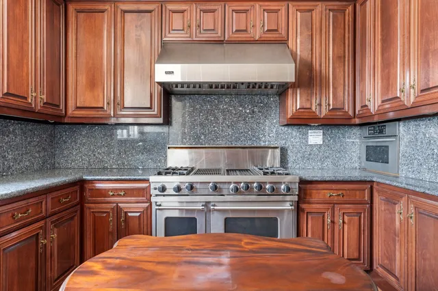 a kitchen with granite countertop wood cabinets stainless steel appliances and a sink