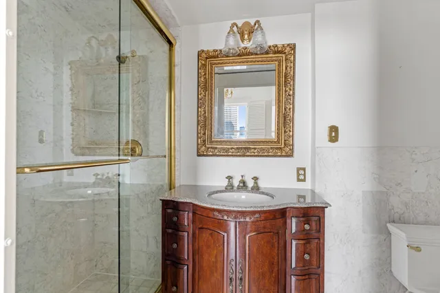 a bathroom with a granite countertop sink a toilet and a mirror