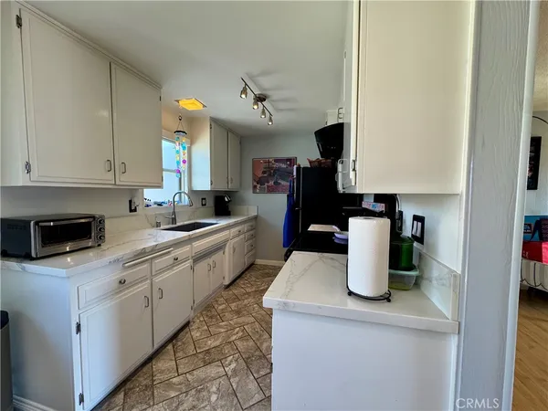 a kitchen with a sink a stove top oven and white cabinets