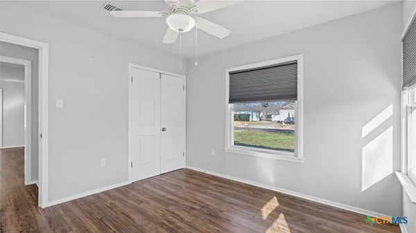 a view of an empty room with wooden floor and a window