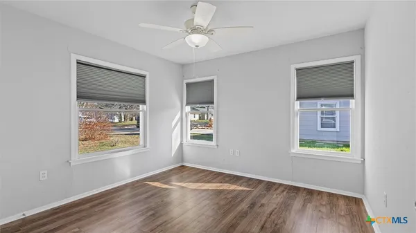 a view of an empty room with window and wooden floor