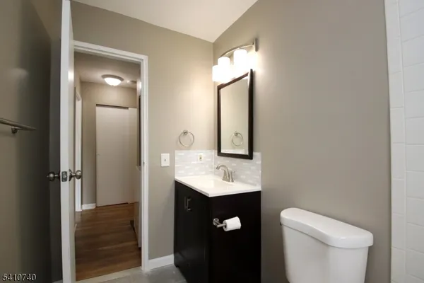 a bathroom with a toilet sink vanity and mirror