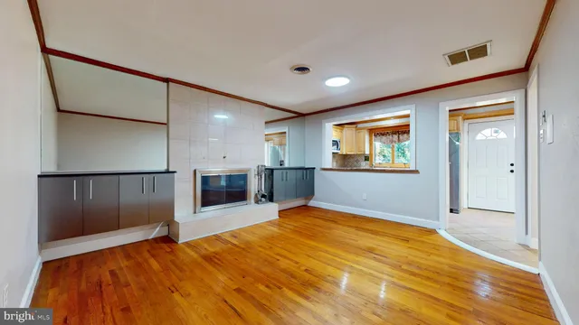 a view of an empty room with wooden floor and window