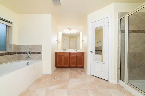 a spacious bathroom with a tub sink shower and mirror