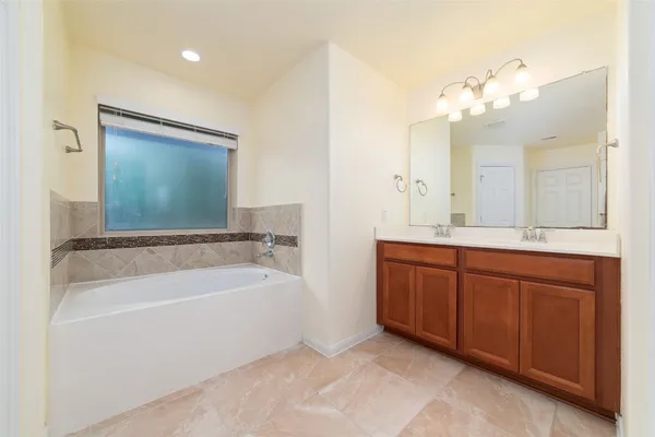 a spacious bathroom with a tub sink and mirror
