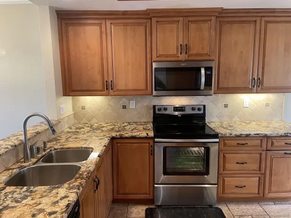 a kitchen with granite countertop a sink stainless steel appliances and cabinets