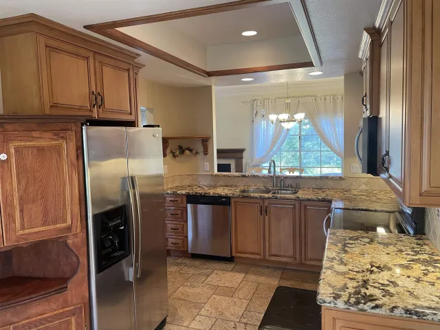 a kitchen with stainless steel appliances granite countertop a refrigerator and a stove top oven