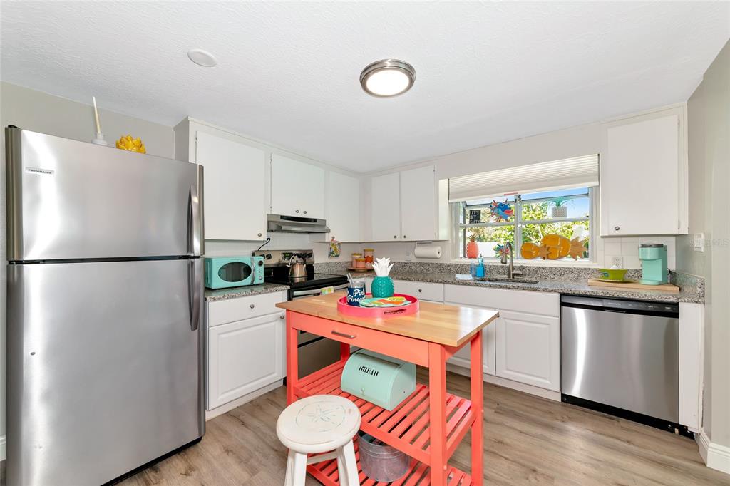 5948 Mirror Lake Road Sarasota, FL 34233 - Photo 24 of 50 a kitchen with stainless steel appliances a refrigerator a sink a stove a dining table and chairs