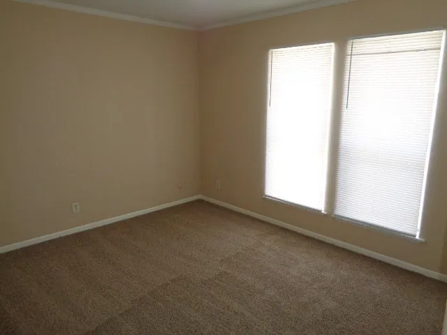 an empty room with a chandelier fan and windows