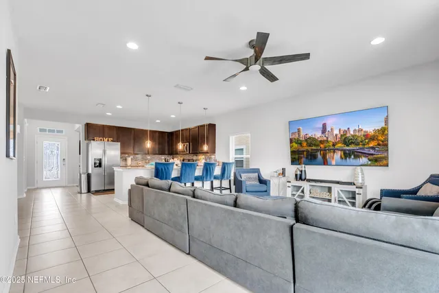 a living room with furniture and a flat screen tv with kitchen view