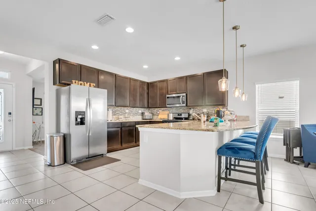 a kitchen with refrigerator and chairs