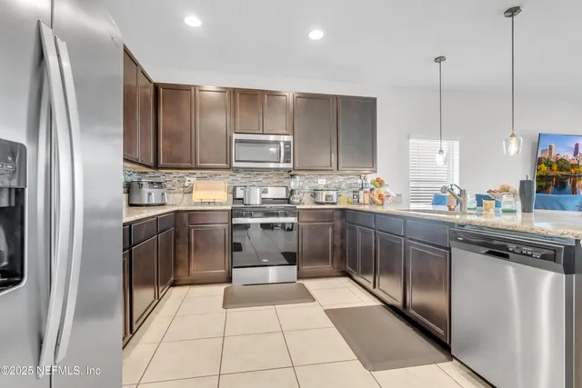 a kitchen with stainless steel appliances granite countertop a refrigerator a stove a sink and a microwave