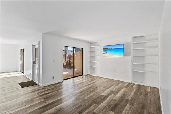 an empty room with wooden floor closet and windows