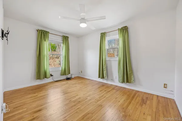a view of an empty room with a window and wooden floor