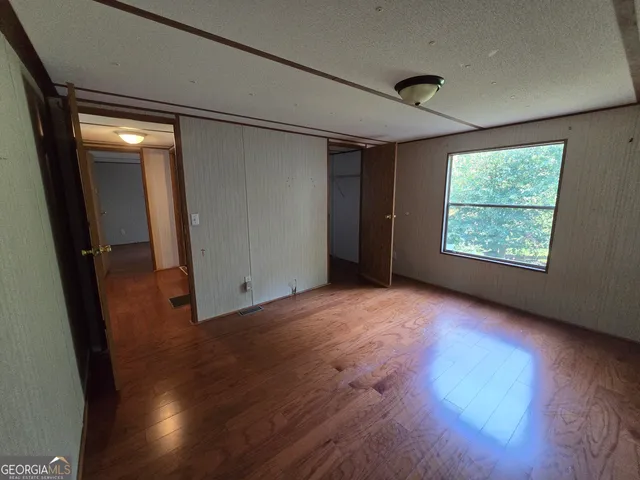 a view of empty room with wooden floor and fan