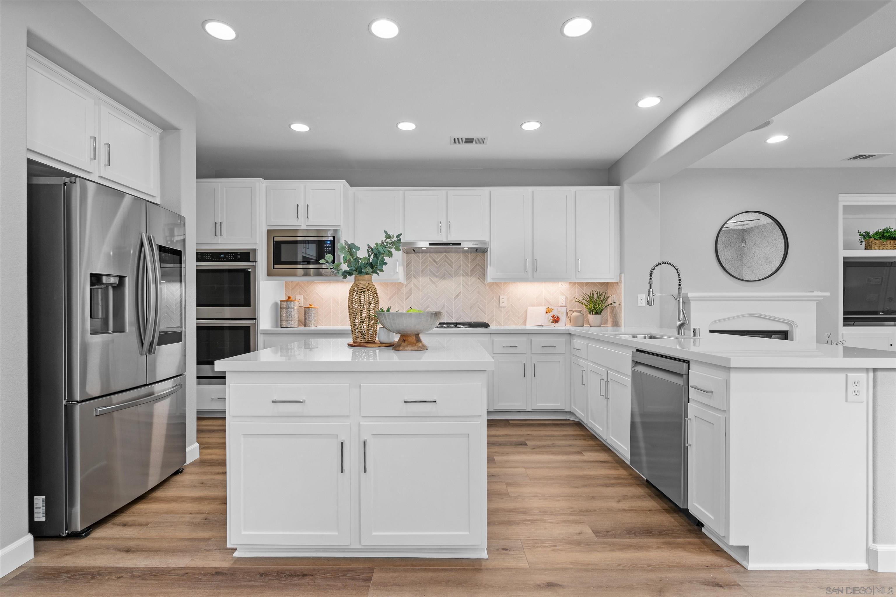 a kitchen with white cabinets stainless steel appliances and a counter top space