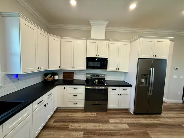 a kitchen with granite countertop a refrigerator stove and sink