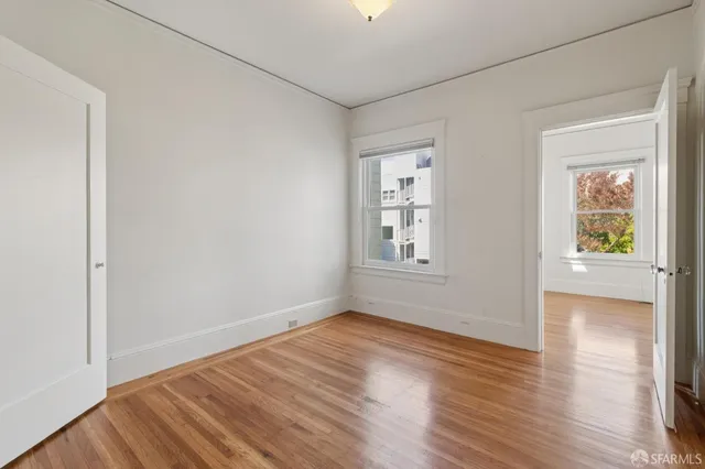 a view of an empty room with wooden floor and a window