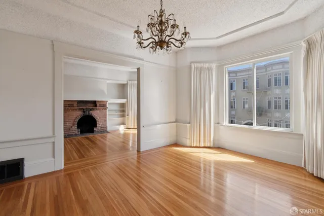 a view of empty room with wooden floor and fireplace